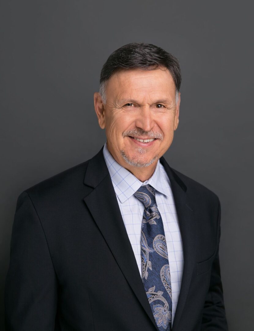 A man in suit and tie standing next to wall.