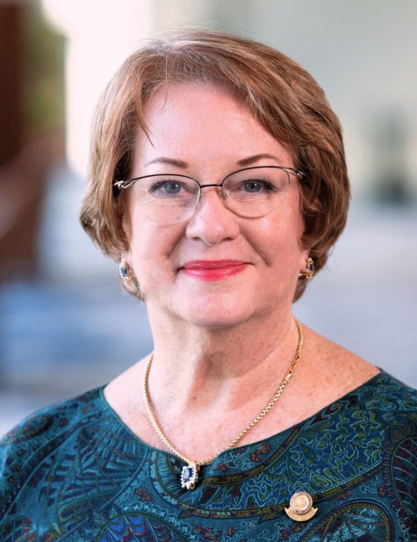 A woman with short hair wearing glasses and smiling.