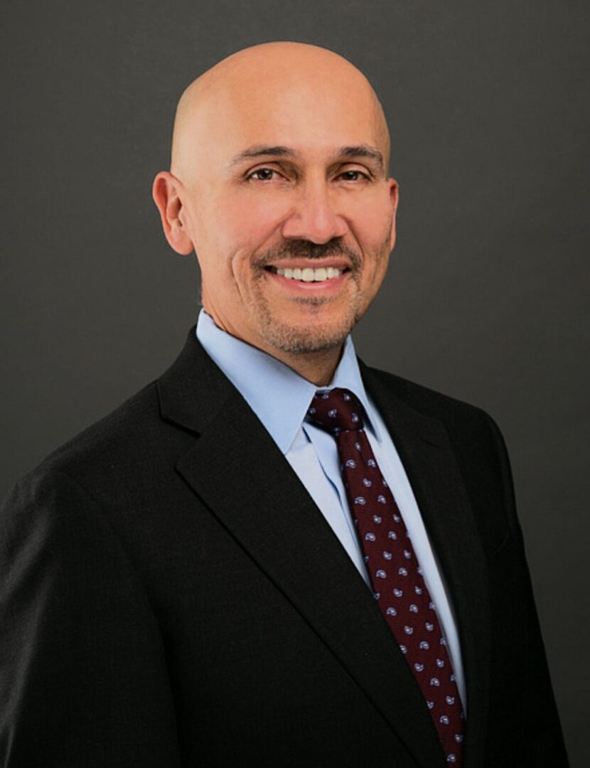 A man in a suit and tie smiling for the camera.