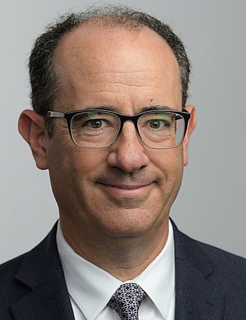 A man with glasses and a suit on.