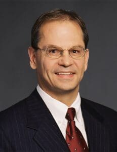 A man in suit and tie smiling for the camera.