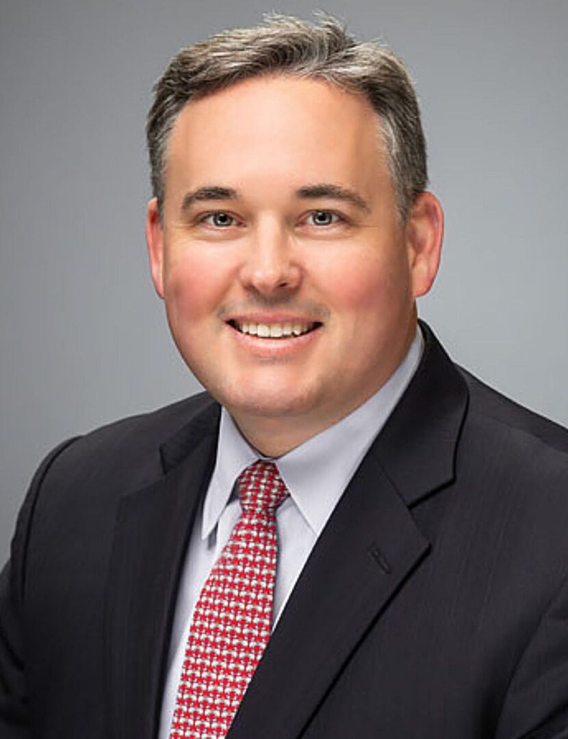 A man in suit and tie smiling for the camera.