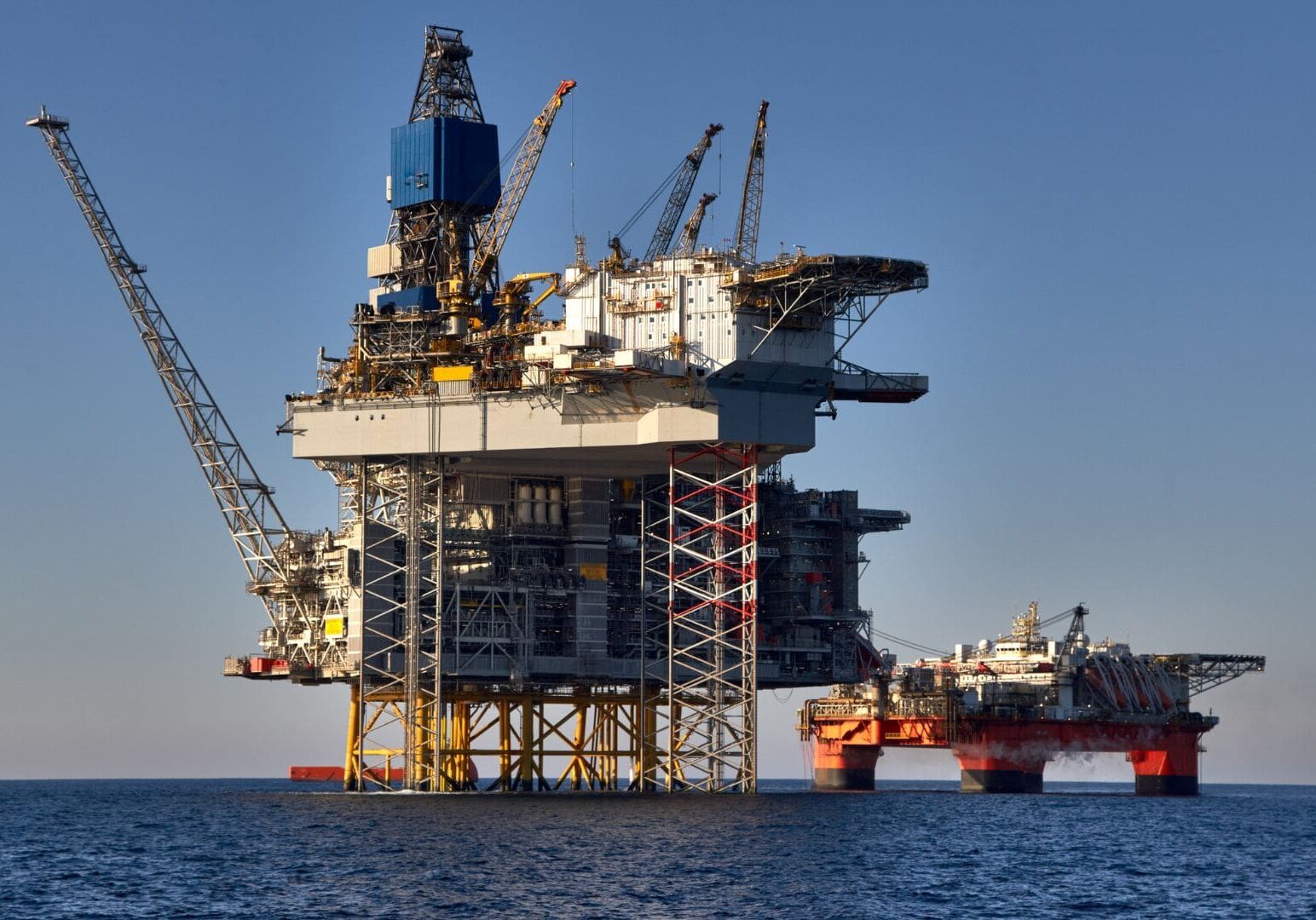 A large rig is in the ocean near an oil platform.